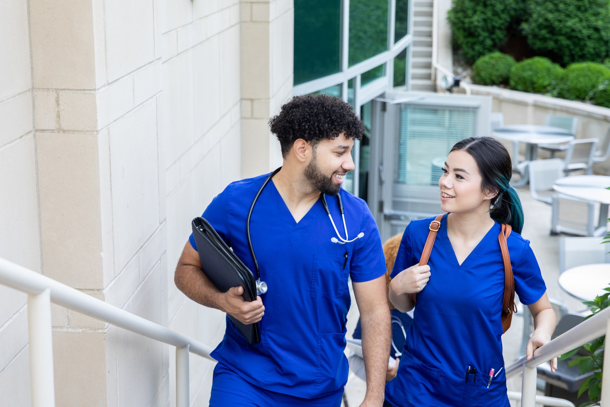 Nursing students wearing blue scrubs talking and walking to class together